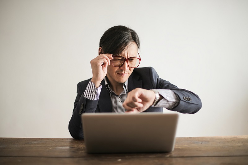 Man working on laptop looking at his watch